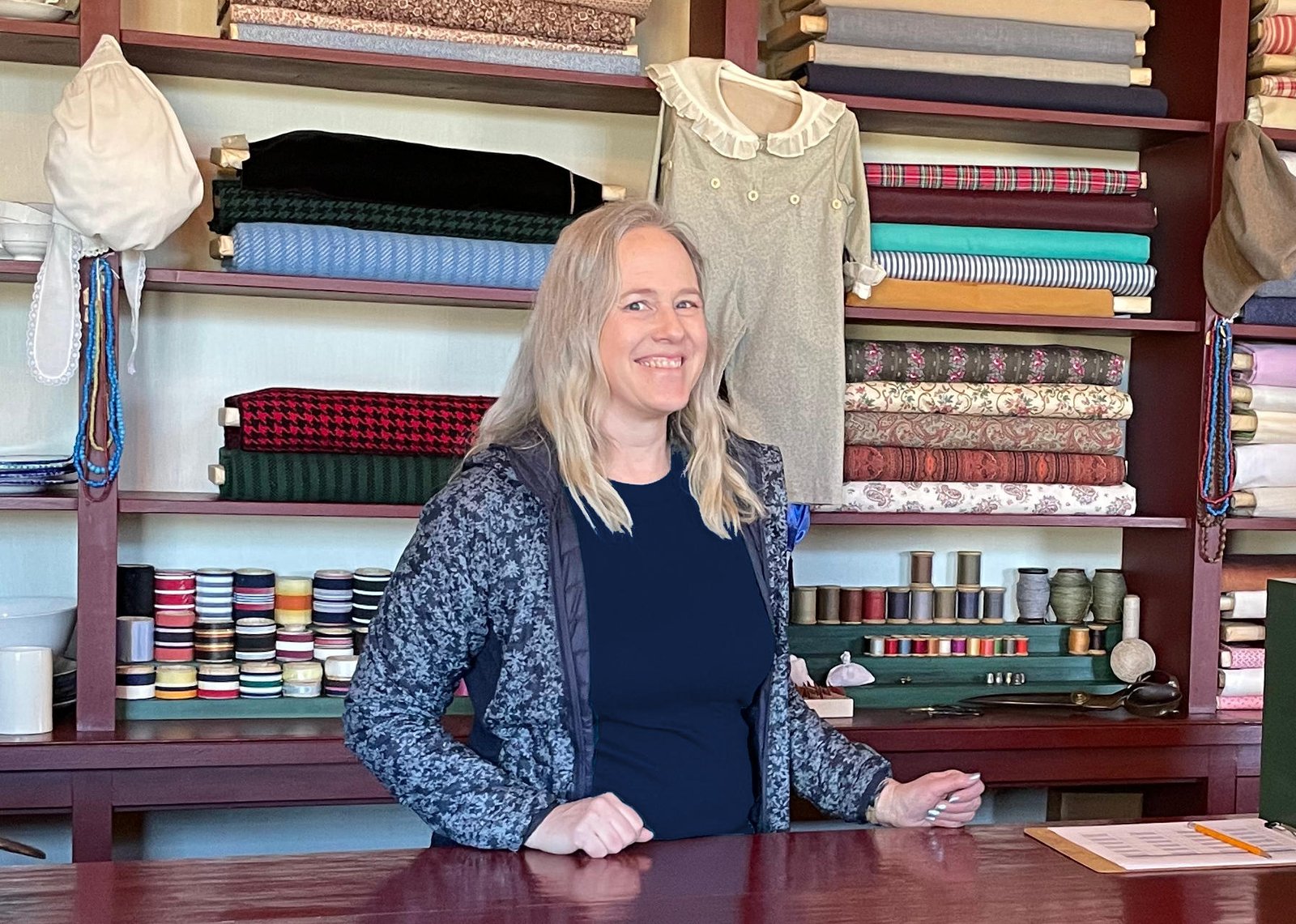 Ami Fullmer Chopine at the reconstructed general store in Nauvoo, surrounded by period textiles and dry goods